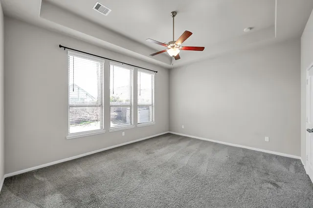 an empty room with a ceiling fan and window