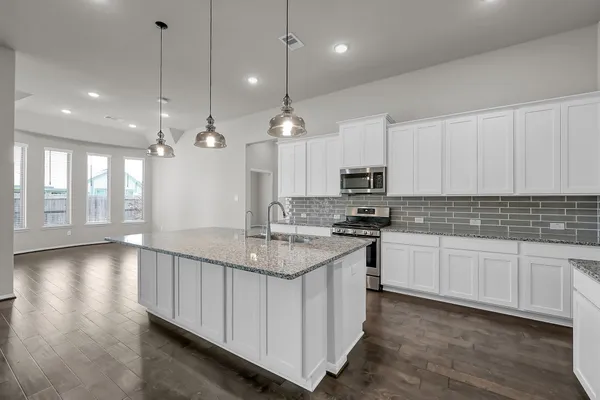 a kitchen with kitchen island granite countertop a sink cabinets and stainless steel appliances