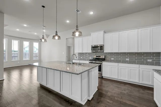 a kitchen with kitchen island granite countertop a sink cabinets and stainless steel appliances