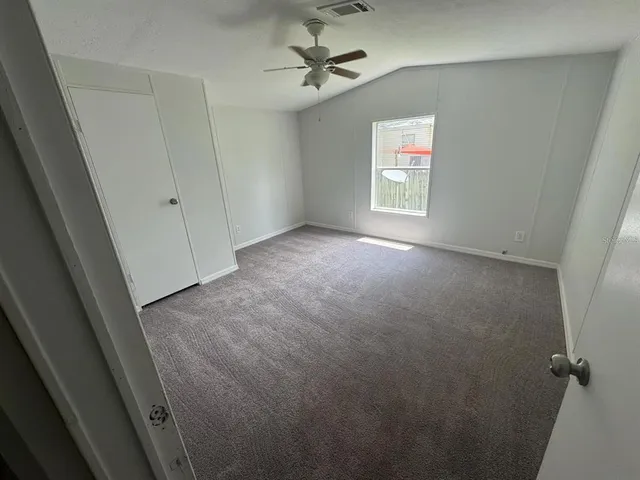 an empty room with windows and ceiling fan