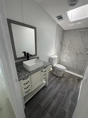 a bathroom with a granite countertop sink a toilet a mirror and vanity
