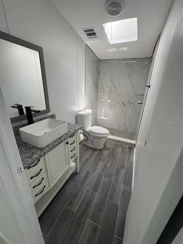 a bathroom with a granite countertop sink toilet and a mirror