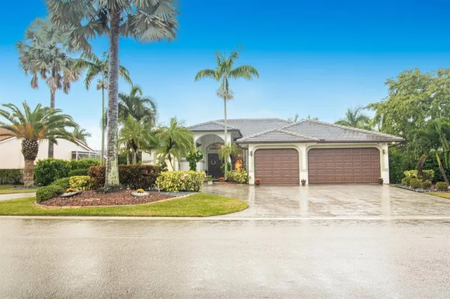 a view of a house with a yard and palm trees