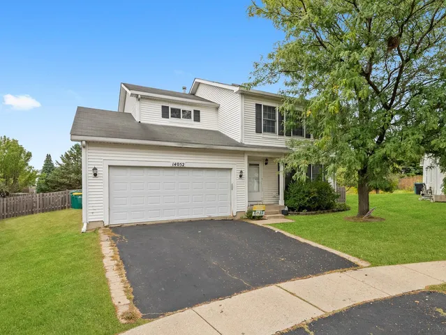 a front view of a house with a garden and trees