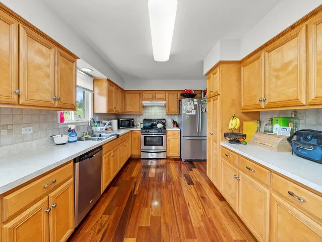 a kitchen with granite countertop wooden floors stainless steel appliances a sink and cabinets