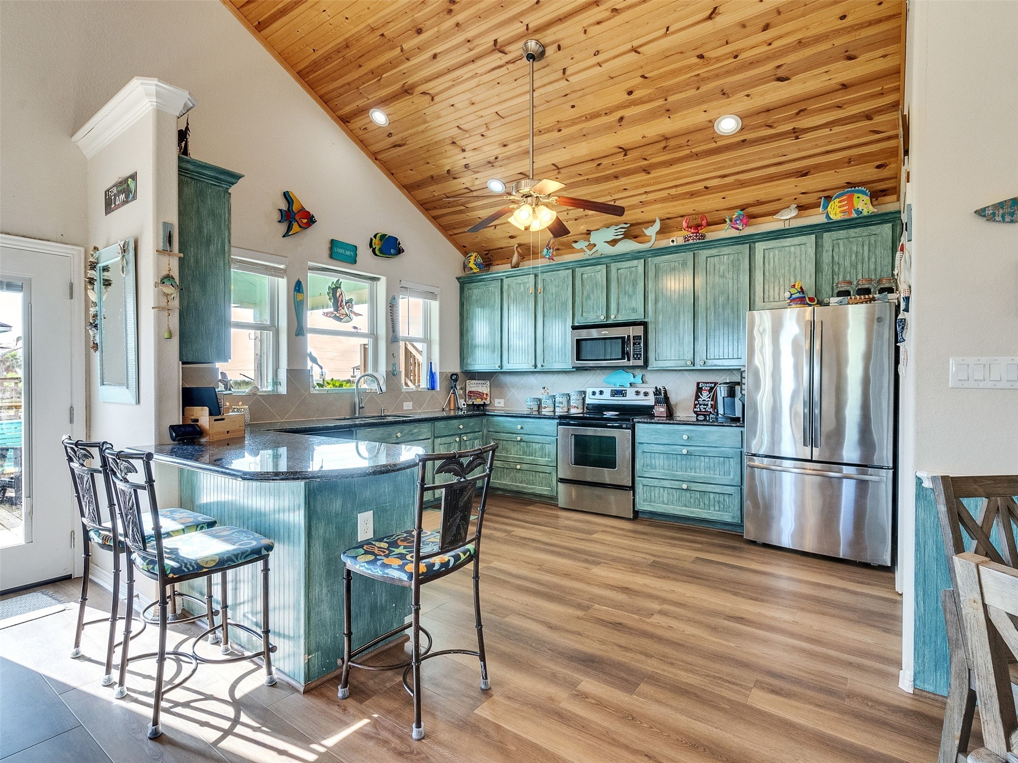 4710 Palm Street Freeport, TX 77541 - Photo 14 of 23 a kitchen with stainless steel appliances granite countertop a refrigerator a stove a sink a dining table and chairs with wooden floor
