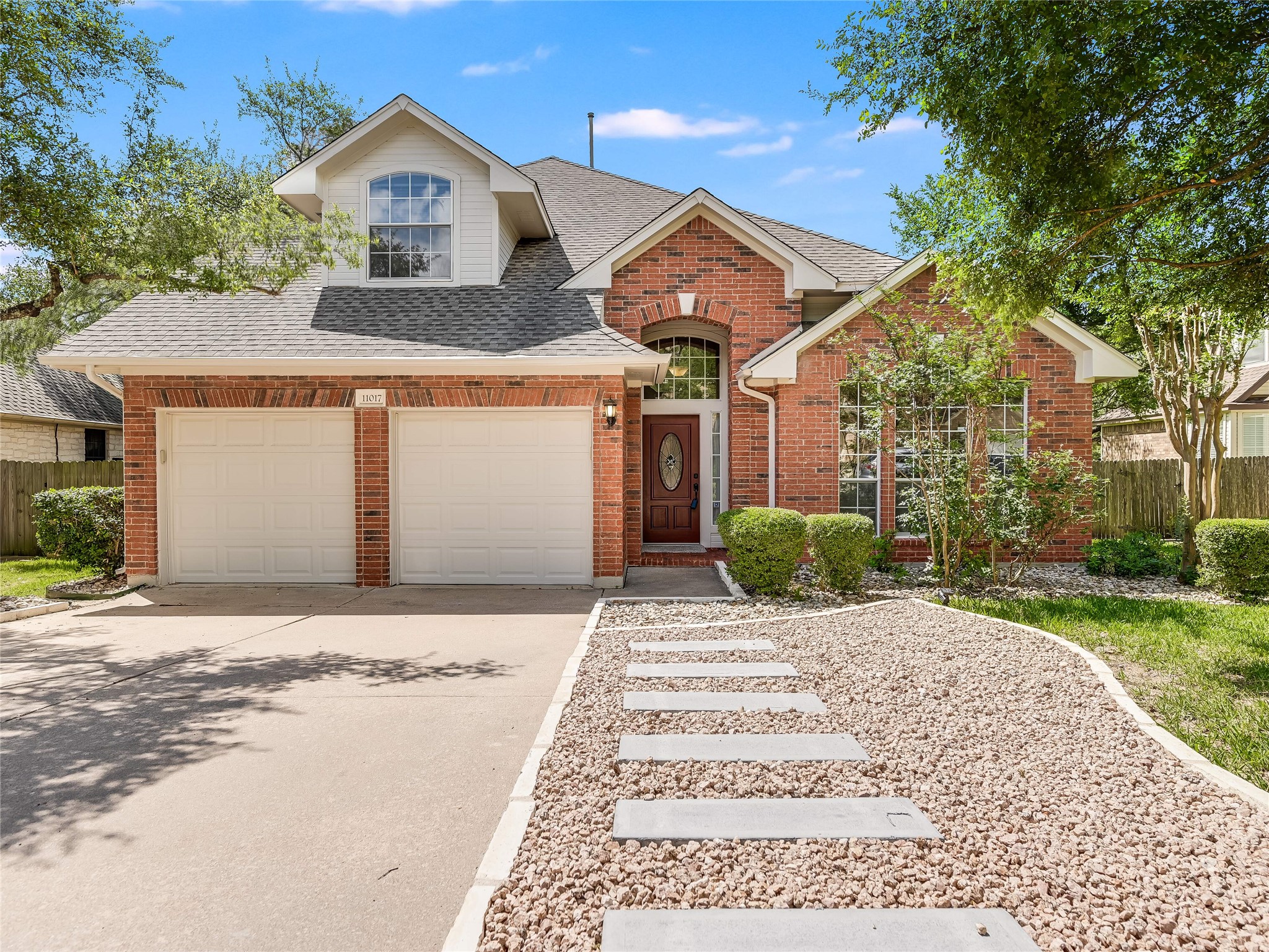 Brick facade residence with a two-car garage, arched entry, and a dormer window