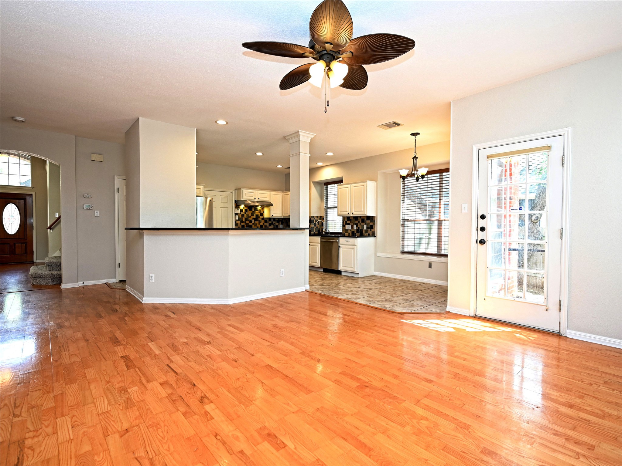11017 Rio Vista Drive Austin, TX 78726 - Photo 16 of 38 Expansive wood-finish flooring extending into a kitchen with stainless steel appliances, light cabinetry, and dark backsplash