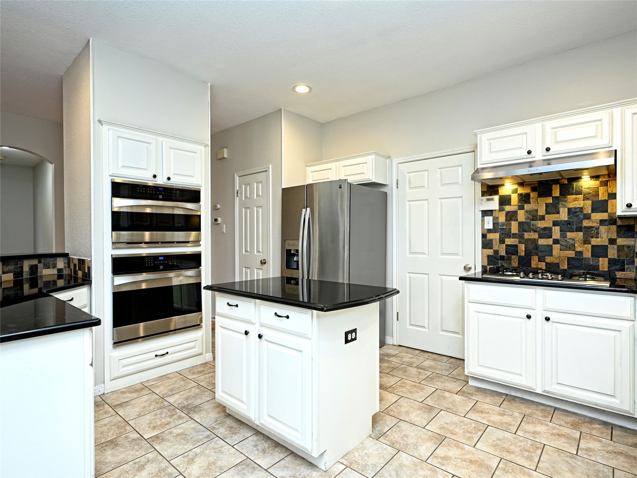 11017 Rio Vista Drive Austin, TX 78726 - Photo 17 of 38 Kitchen featuring white cabinetry, dark countertops, a mosaic tile backsplash, stainless steel appliances, and tile flooring