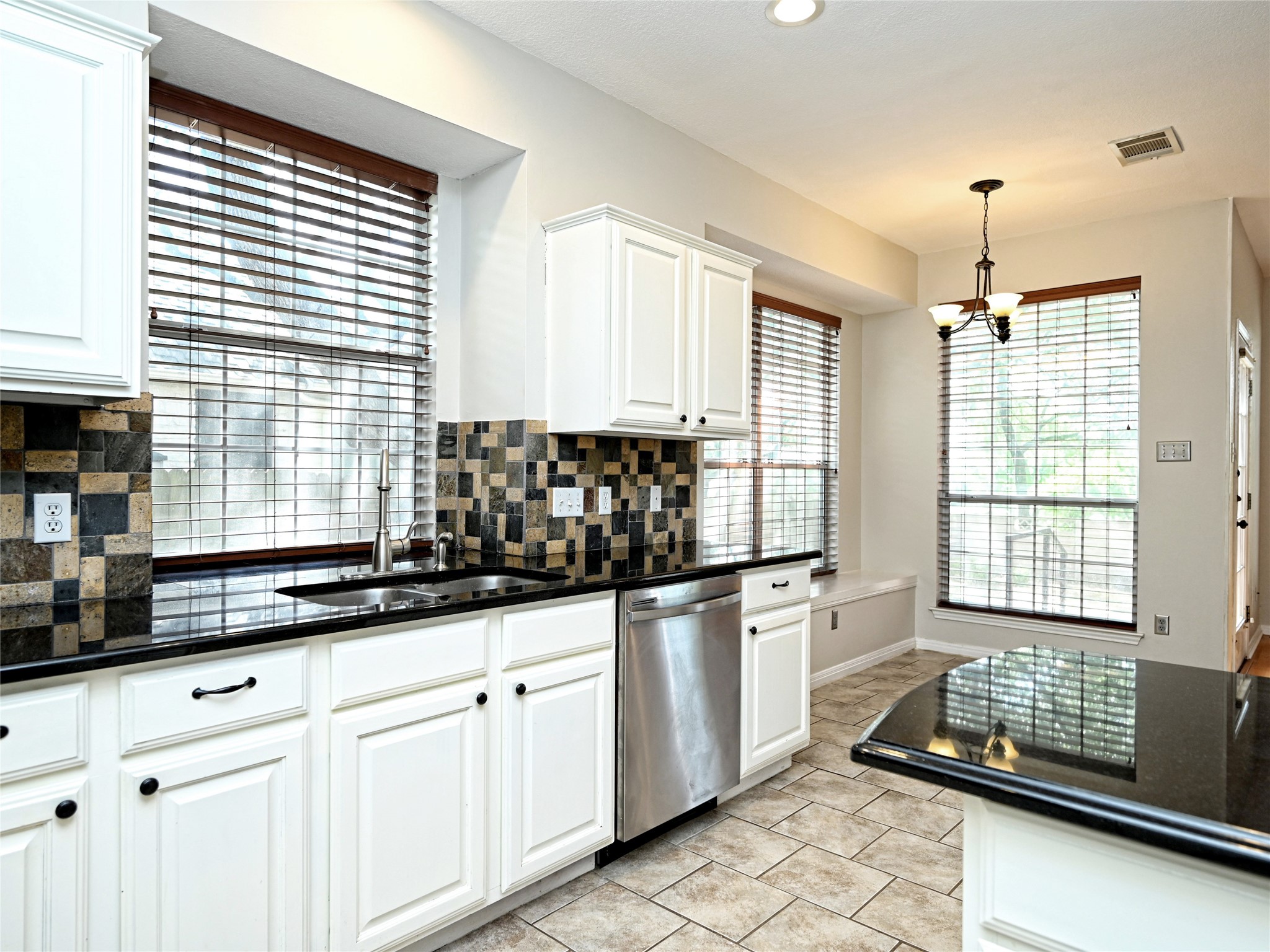 11017 Rio Vista Drive Austin, TX 78726 - Photo 18 of 38 Kitchen featuring white cabinetry, black stone countertops, and a mosaic tile backsplash