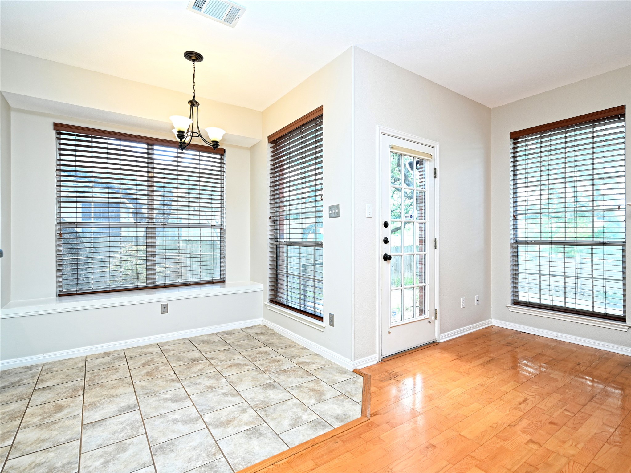 11017 Rio Vista Drive Austin, TX 78726 - Photo 20 of 38 Bright interior space featuring a multi-pane glass door, two large windows with blinds, a built-in window bench, a chandelier, and a combination of tile and wood-finish flooring