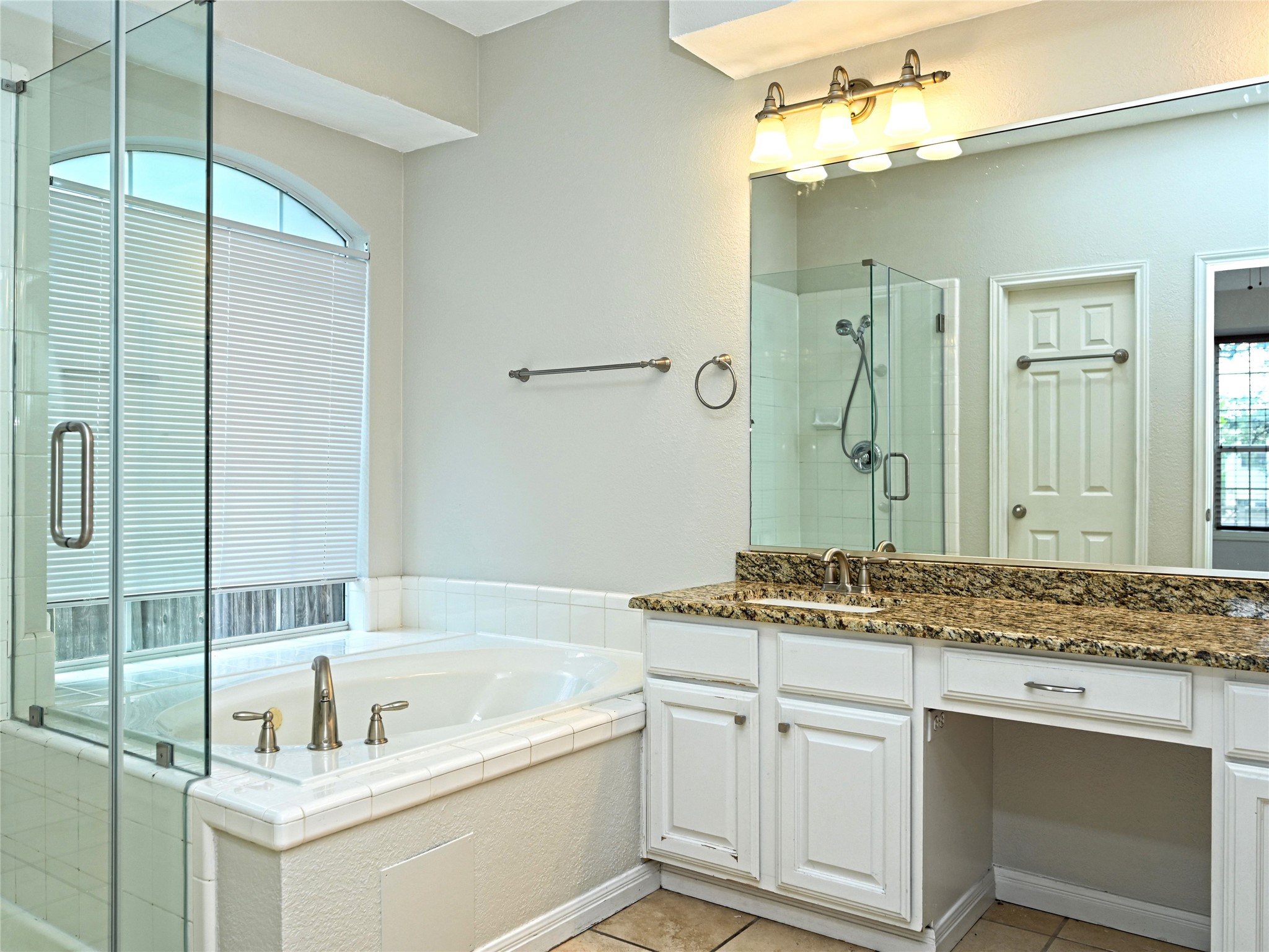 11017 Rio Vista Drive Austin, TX 78726 - Photo 26 of 38 Bathroom featuring a built-in soaking tub, a separate glass-enclosed shower, and a vanity with a granite countertop