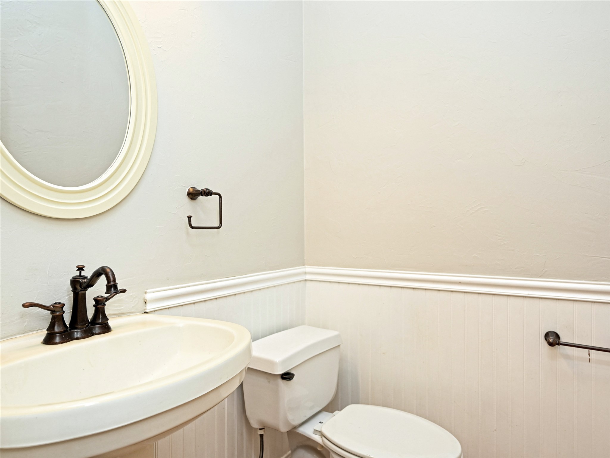11017 Rio Vista Drive Austin, TX 78726 - Photo 32 of 38 Pedestal sink with oil-rubbed bronze faucet, oval mirror, and beadboard wainscoting