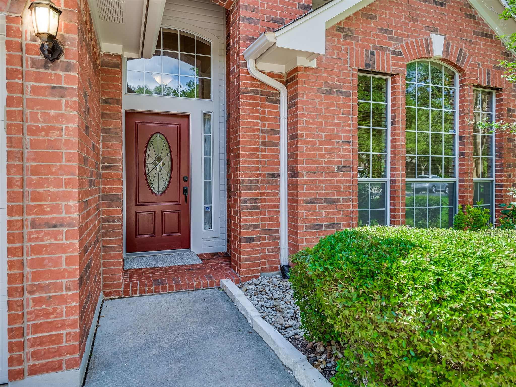 11017 Rio Vista Drive Austin, TX 78726 - Photo 4 of 38 Traditional brick exterior featuring a recessed entry with a red door, oval leaded glass insert, and transom window
