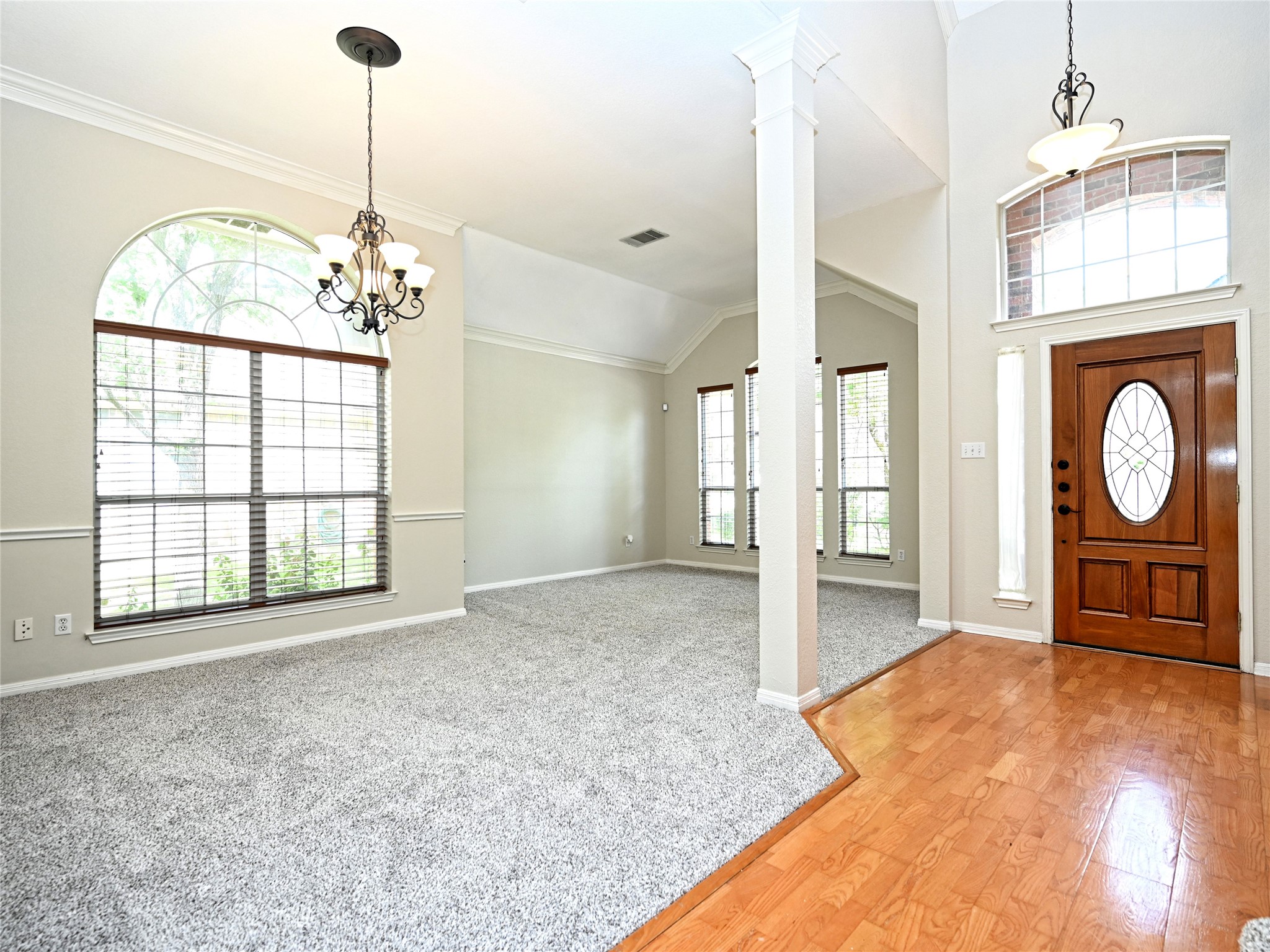 11017 Rio Vista Drive Austin, TX 78726 - Photo 6 of 38 Entryway featuring a wood-panel door with oval leaded glass insert, wood-finish flooring, and a decorative chandelier
