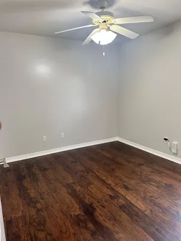 a view of a room with wooden floor and a ceiling fan