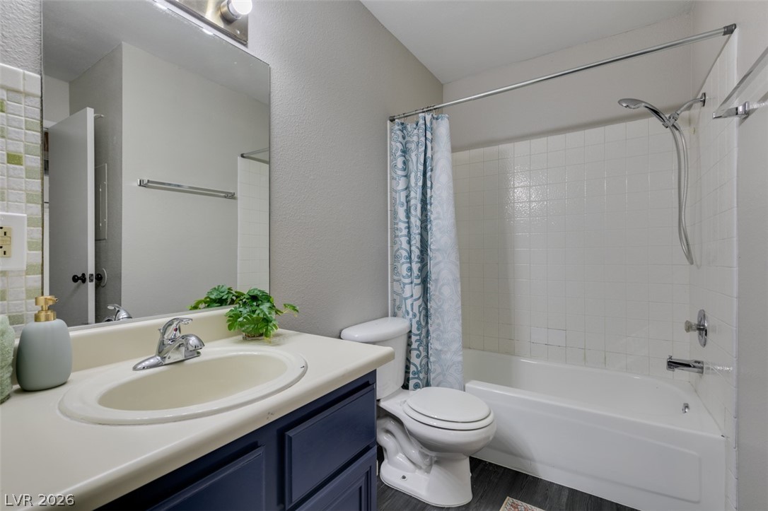 810 North Sloan Lane, Unit 103 Las Vegas, NV 89110 - Photo 5 of 16 Bathroom with toilet, shower / bath combination with curtain, vanity, wood finished floors, and a textured wall