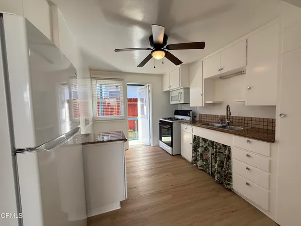 a kitchen with granite countertop a sink cabinets stainless steel appliances and a window