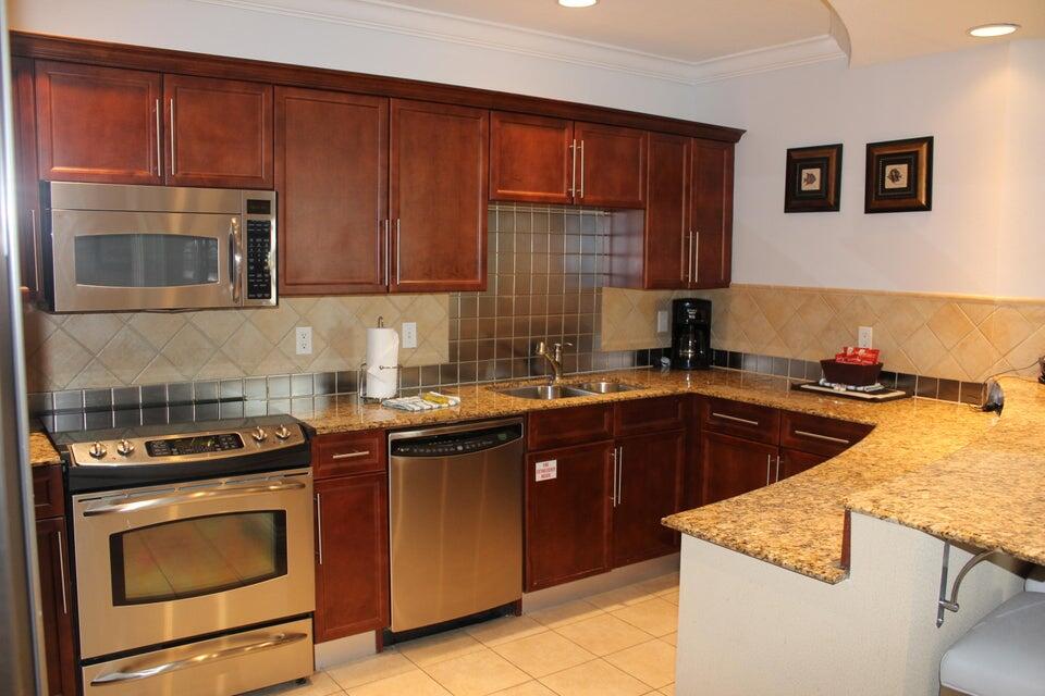 10 Harbor Boulevard, Unit 203B Destin, FL 32541 - Photo 6 of 18 a kitchen with stainless steel appliances wooden cabinets and a stove top oven