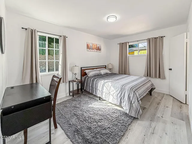 a bedroom with a bed and a desk next to a window