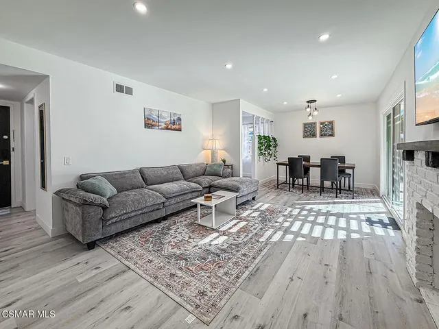 a living room with furniture and a dining table with wooden floor