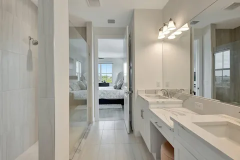 a en suite bathroom with a double vanity sink a mirror and shower