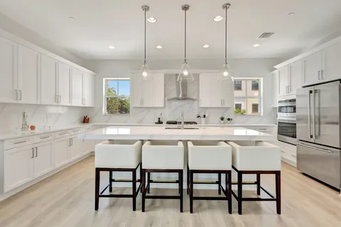 a kitchen with stainless steel appliances granite countertop a table chairs sink refrigerator and cabinets