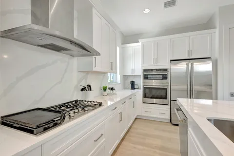 a kitchen with stainless steel appliances kitchen island granite countertop a refrigerator and a stove top oven