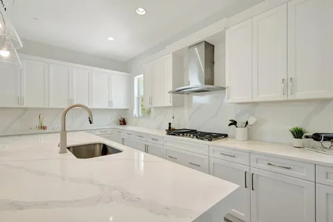 a kitchen with granite countertop a sink a stove and cabinets