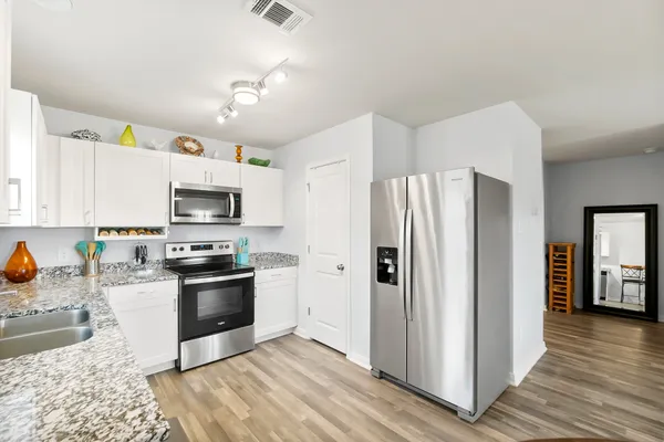 a kitchen with granite countertop a sink stainless steel appliances and white cabinets