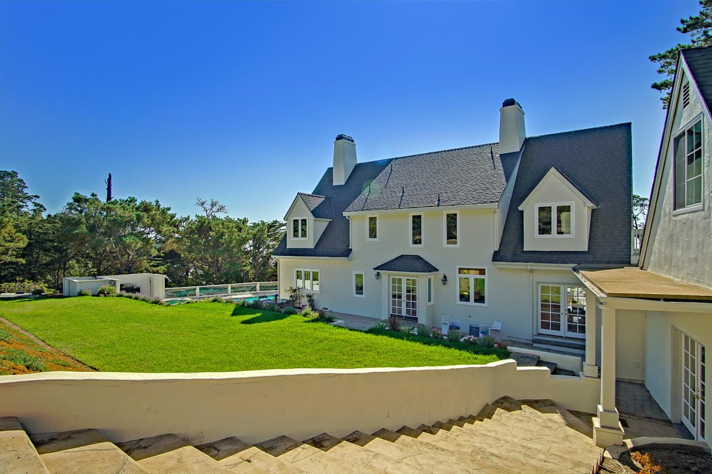21 Mentone Road Carmel, CA 93923 - Photo 72 of 80 a view of a white house with a big yard and potted plants