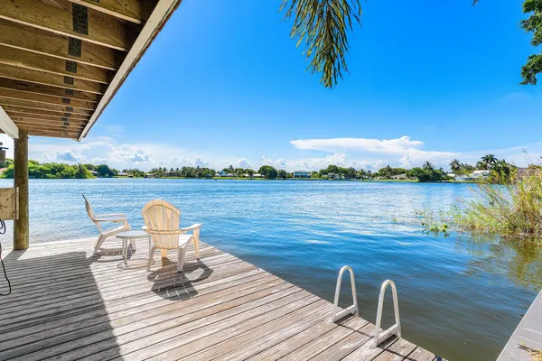 a view of a lake with tables and chair and wooden floor