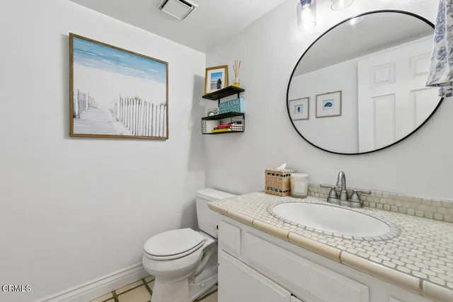 a bathroom with a granite countertop toilet a sink and a mirror