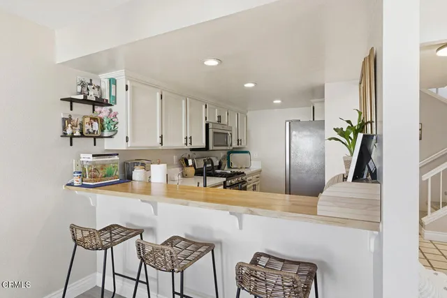 a kitchen with granite countertop a refrigerator a stove a sink and chairs