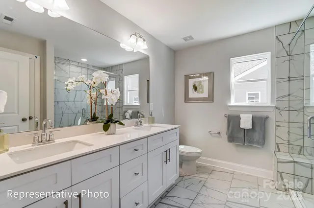 a spacious bathroom with a double vanity sink toilet and a mirror