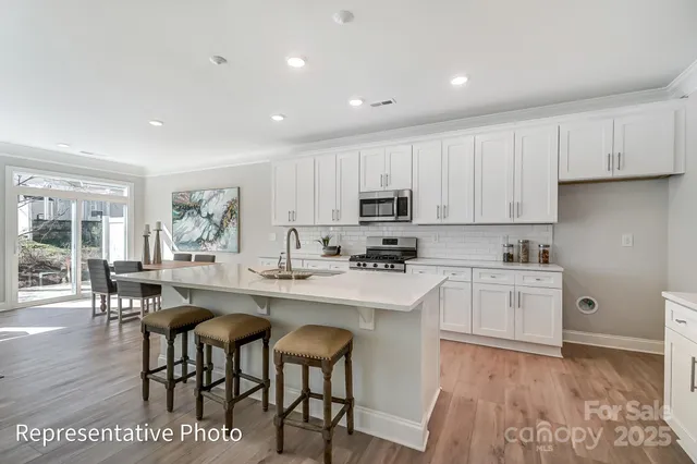 a kitchen with white cabinets appliances and wooden floor