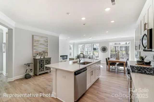 a large kitchen with stainless steel appliances a stove a sink dishwasher and a dining table with the kitchen view