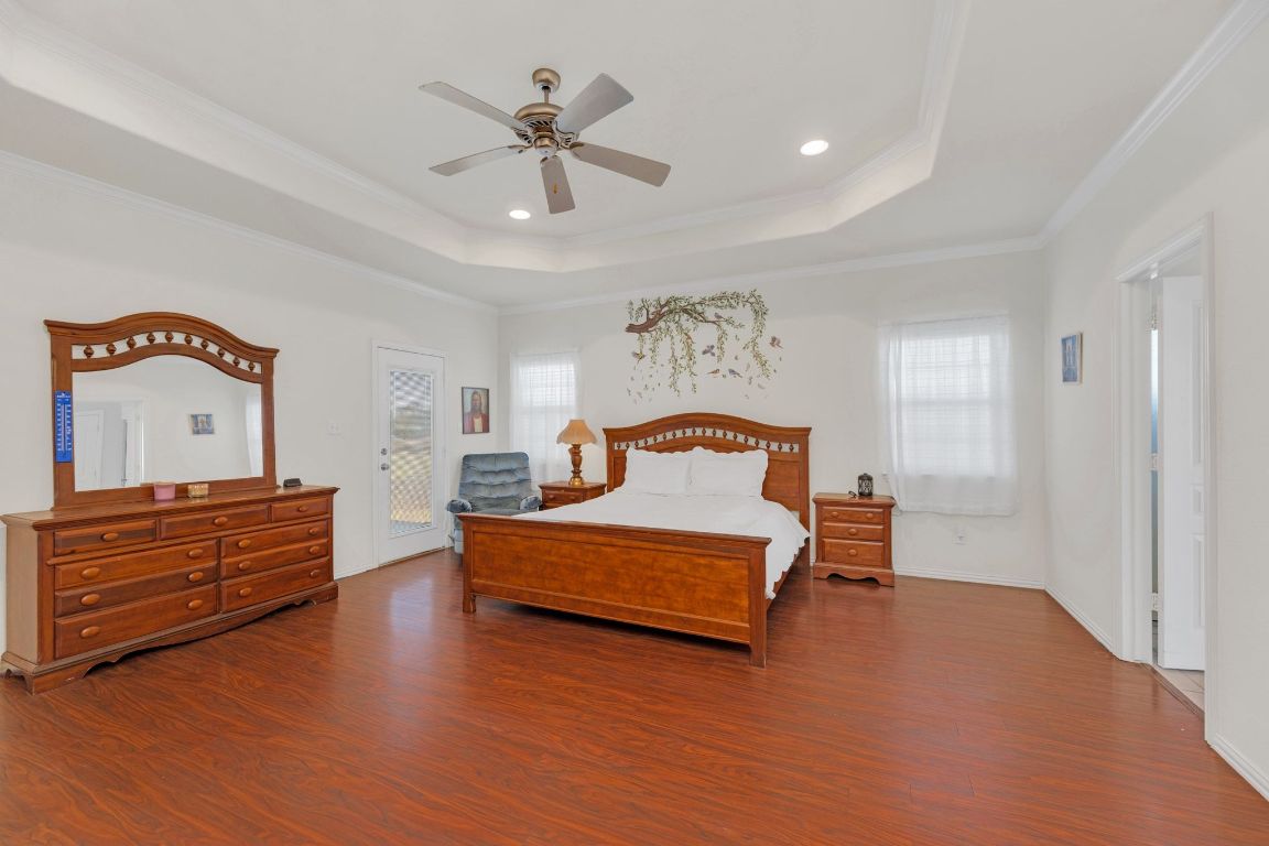 1949 Farm To Market Road 619 Elgin, TX 78621 - Photo 15 of 36 Bedroom featuring dark wood-style floors, a raised ceiling, ceiling fan, ornamental molding, and recessed lighting