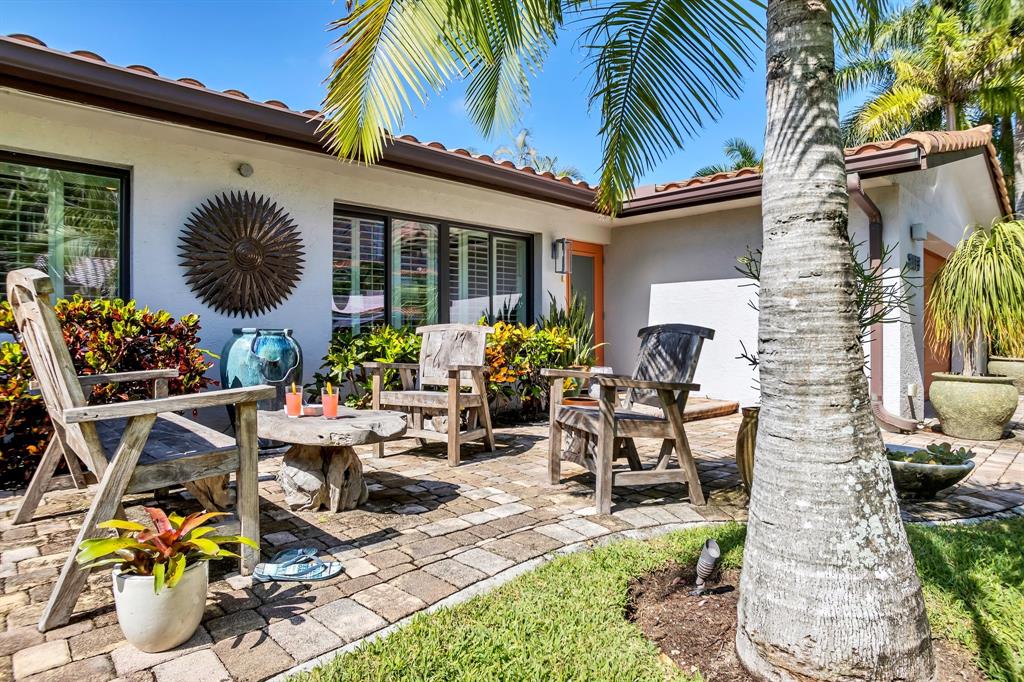 2013 Northeast 32nd Avenue Fort Lauderdale, FL 33305 - Photo 4 of 50 a view of a patio with table and chairs potted plants and a palm tree