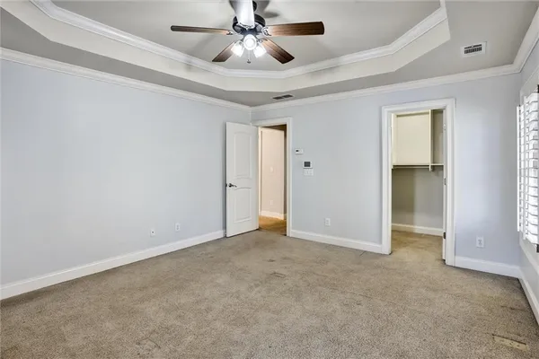 an empty room with closet and a ceiling fan