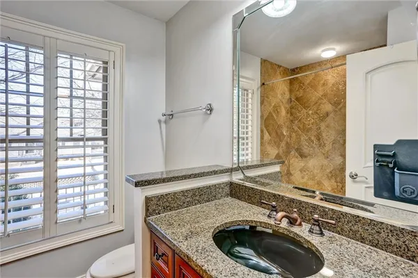 a bathroom with a granite countertop sink and a washing machine