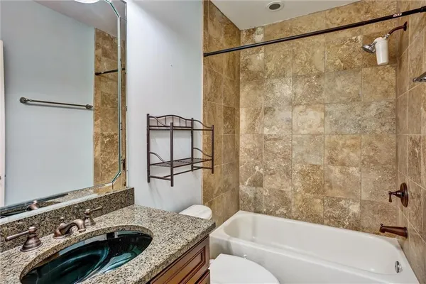 a bathroom with a granite countertop sink a toilet and shower