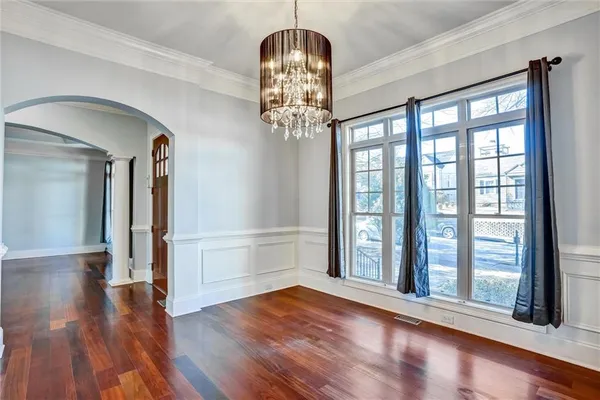 a view of a room with wooden floor chandelier and windows