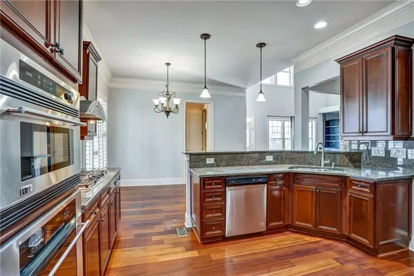 a kitchen with stainless steel appliances granite countertop a sink a stove and a wooden floors