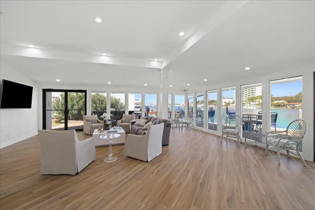 a living room with lots of furniture a wooden floor and a large window