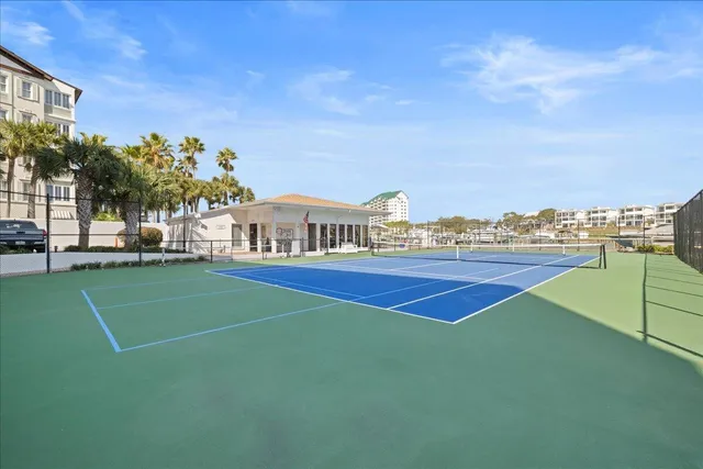 a view of a tennis ground with large trees