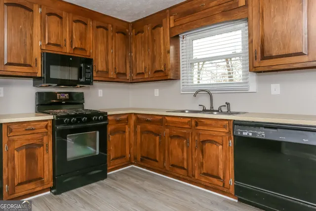 a kitchen with stainless steel appliances granite countertop a stove a sink dishwasher and a microwave oven with wooden cabinets