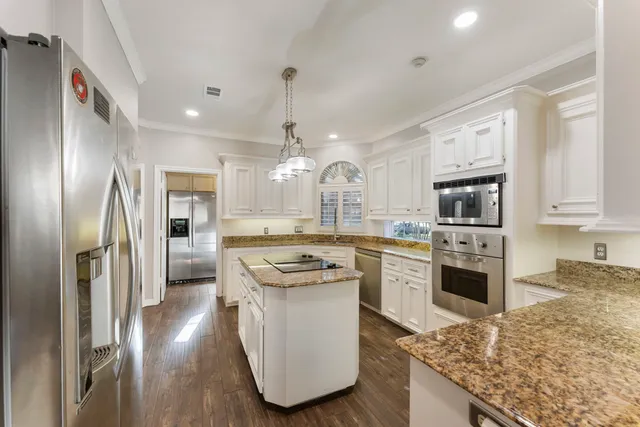 a kitchen with stainless steel appliances granite countertop a refrigerator a stove and a sink