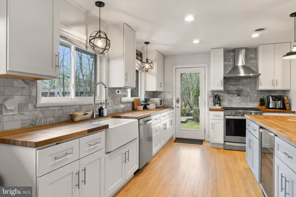 a kitchen with a sink dishwasher a stove a microwave oven and a dining table with wooden floor