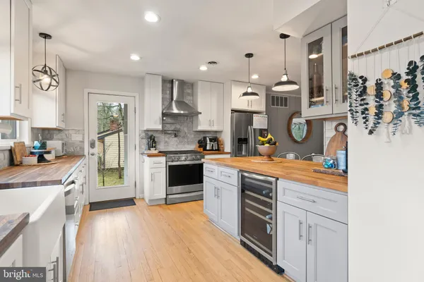 a kitchen with stainless steel appliances granite countertop a refrigerator a sink dishwasher a stove and white cabinets with wooden floor